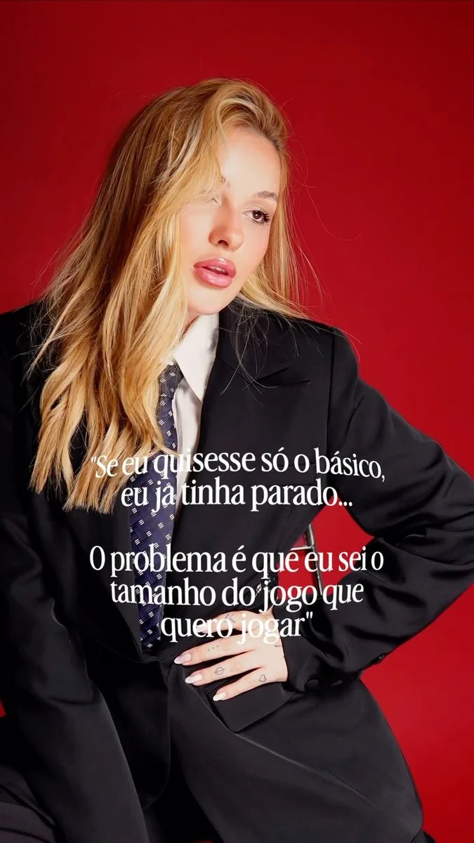 Amanda Roberta em ensaio executivo com terno preto e fundo vermelho